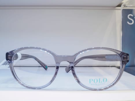 Pair of transparent eyeglasses with a thick grey frame is displayed on a white surface, showcasing their modern and stylish design