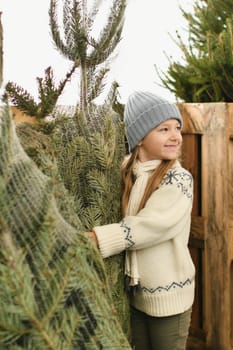 A girl chooses for buying a Christmas tree in the market.
