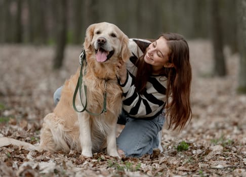 Teenage Girl Sits With Golden Retriever In Park During Autumn