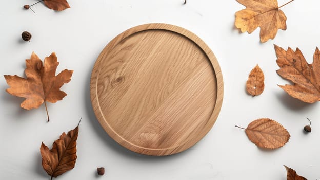 A round wooden serving platter rests at the center, encircled by various autumn leaves in shades of brown and gold on a light surface. The natural textures of the wood and the leaves create an inviting autumnal aesthetic.