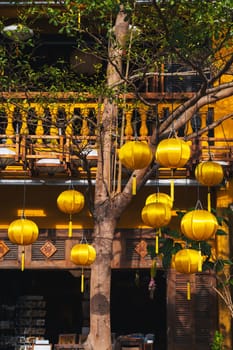 facade of an ancient Asian house decorated with yellow hanging Chinese lanterns for a holiday in old town in Hoi An in Vietnam