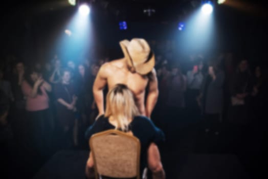 blurred silhouette of a male stripper on the stage of a night club arranging a performance