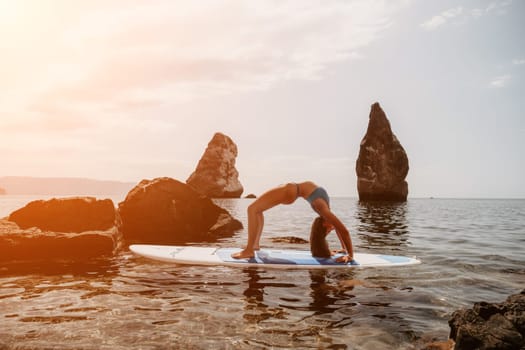 Woman sup yoga. Middle age sporty woman practising yoga pilates on paddle sup surfboard. Female stretching doing workout on sea water. Modern individual hipster outdoor summer sport activity