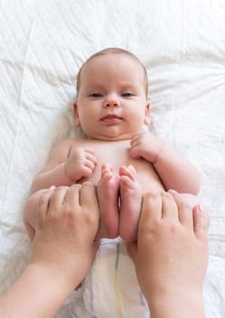 Mother's hands work on baby's legs. Concept of healing touch for colic relief