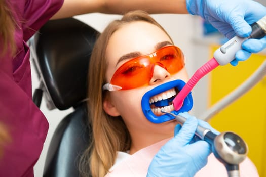 Professional teeth cleaning for young female patient at the modern dental clinic.