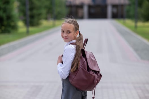Portrait of caucasian schoolgirl in uniform and with backpack outdoors