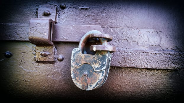 Old rusty padlock on a metal door close-up. Added vintage camera effect