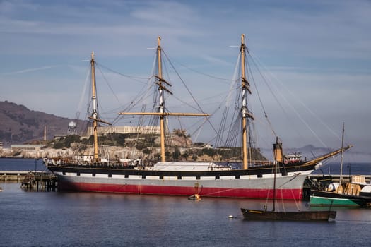 Capture the essence of maritime nostalgia with this splendid image of a vintage sailing ship and an old boat anchored under a vivid blue sky. The classic designs of the vessels are beautifully complemented by the expanse of azure overhead, making this photo a perfect fit for projects related to travel, history, or nautical adventures.