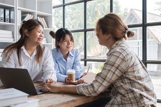 Asian College groups of students using laptop, tablet, studying together with notebooks documents paper for report near windows in classroom. Happy young study for school assignment