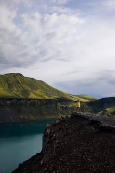 This photo shows a backpacker girl contemplating the beauty of Blahylur Lake in Iceland. She is standing with her side to the camera, one leg forward, and her head turned to the lake and the mountain in the background. The sky is cloudy, creating a sense of mystery and intrigue. This photo is perfect for use in travel and nature photography. It could be used to illustrate a story about hiking in Iceland, or it could simply be used to create a sense of wonder.
