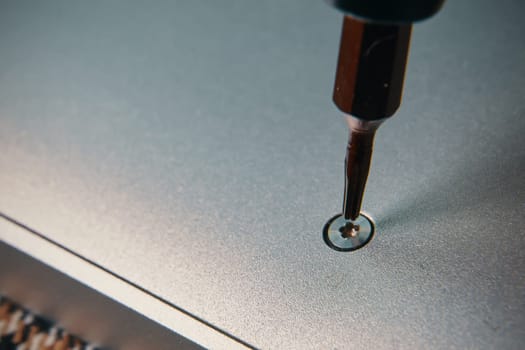 A detailed closeup view of a screwdriver meticulously aligning a screw into a metallic surface for precise assembly