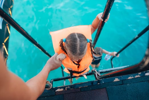 Kids energetically climbing aboard from the water, showcasing swimming safety with bright life jackets
