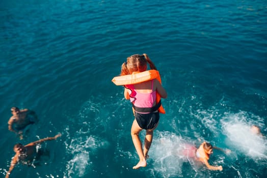 A group of happy children joyfully splashing in the ocean, wearing life vests and enjoying their playful moment