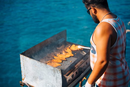 A vibrant and lively summer scene of grilling delicious fish right beside beautiful ocean waters under the sun