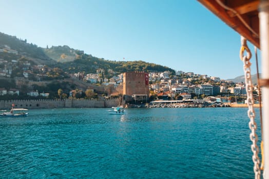 A captured view showcases a historic tower majestically overlooking the tranquil sparkling waters and lush hills
