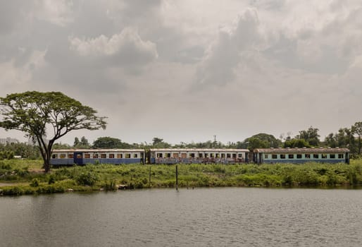 Bangkok, Thailand - May 28,2022 - View of vintage railroad container is parked in wasteland and swamp with sky background. The empty old rusty passenger train and abandoned, Space for text, Selective focus.