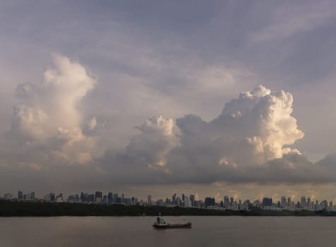 Bangkok, Thailand - 06 Aug 2024 - Beautiful Clouds in the Sky over Large Metropolitan City of Bangkok along Chao praya riverside with cargo ship. View of Skyscrapers and Dramatic Sky before Sunset, Space for text, Selective focus.