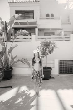 A young girl stands confidently outdoors in a stylish outfit, surrounded by vibrant greenery and plants