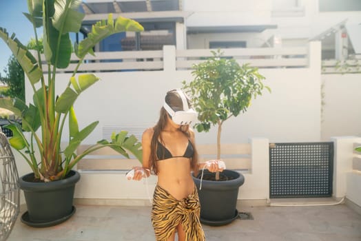 A stylish woman in a bikini enjoys a thrilling outdoor virtual reality experience, combining leisure with tech