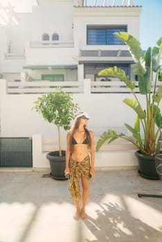 A stylish, fashionable woman revels in a bright, sunny day while enjoying a relaxed atmosphere in a tropical setting