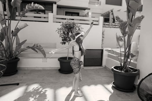 A joyful dancer fully embraces the warm sunlight radiating in a vibrant outdoor space adorned with lush tropical plants