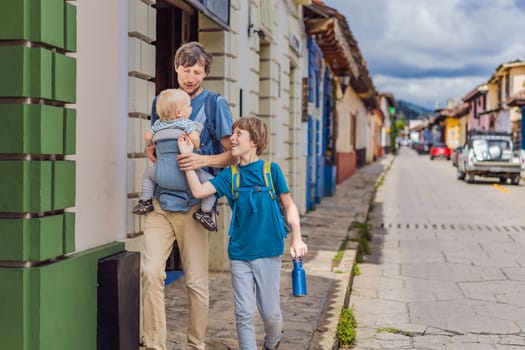 Father and and his two sons, a teenager and a baby tourists walks through the colonial streets San Cristobal de las Casas, Mexico. Cultural exploration, architecture, and travel experience concept.