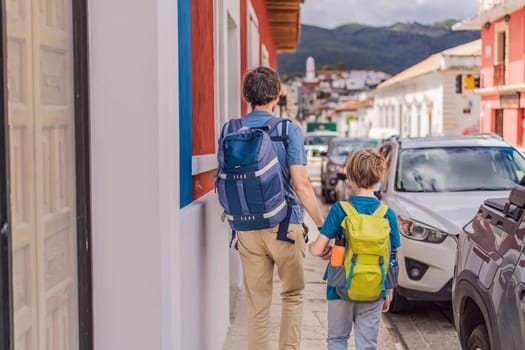 Father and and his two sons, a teenager and a baby tourists walks through the colonial streets San Cristobal de las Casas, Mexico. Cultural exploration, architecture, and travel experience concept.