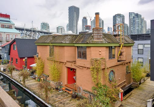 Row of housees on the water with view at downtown of Vancouver, Canada.