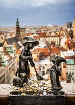 Gnome sculpture in Wroclaw with coins against amazing Wroclaw city view. Tradition dwarf statues of Wroclaw - so-called calling card of the city.