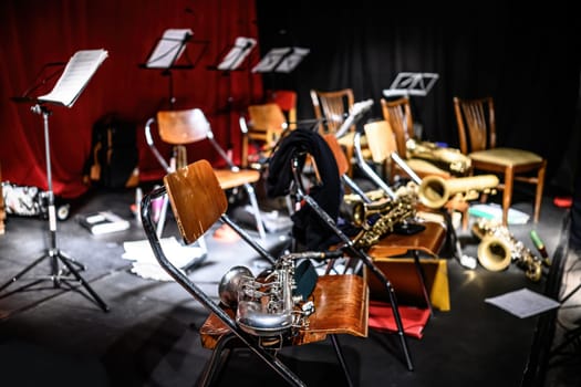 Concert hall stage and saxophones lying on chairs after jazz music live performance. Musical instruments for acoustic show