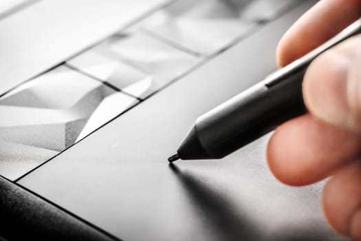 Artist drawing with a pen on an electronic tablet, close up view
