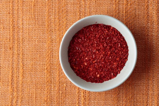 Chilli pepper seedless flakes gochugaru, ingredient for kimchi. Dried red pepper flakes in bowl. Spices and herbs.
