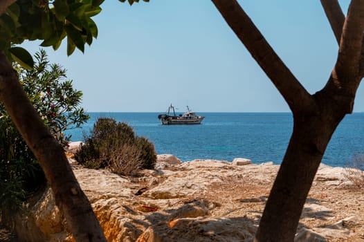 A serene seascape with a boat floating on calm blue waters, framed by rocky coastline and lush greenery, evoking peace and exploration.
