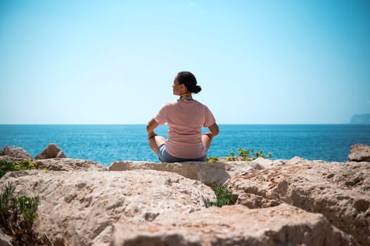 A serene scene of a person meditating on a rocky shore, with a vast blue sea and clear sky in the background, evoking peace and tranquility.