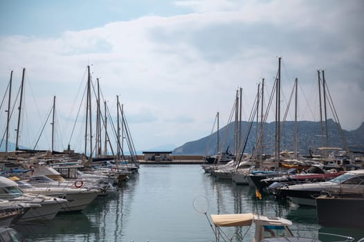 A peaceful marina scene featuring numerous yachts and sailboats, with calm waters and a mountainous backdrop, conveying a sense of leisure and escape.