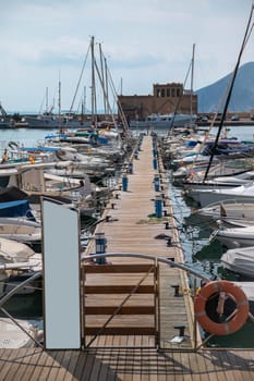 Scenic view of a marina with numerous boats docked along a wooden pier, under a tranquil sky. A perfect setting for sailing enthusiasts.