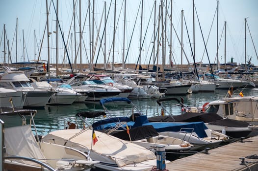 A picturesque view of a bustling marina filled with yachts and sailboats neatly docked, reflecting the serene ambiance of the waterside setting.
