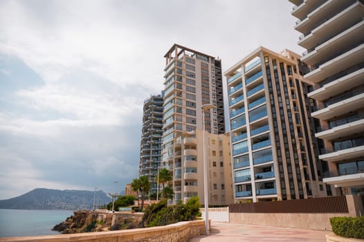 Contemporary high-rise residential buildings by the ocean, featuring stunning architecture and a serene coastal backdrop under a clear sky.