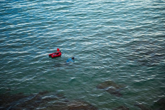 A person snorkeling in tranquil ocean waters near a floating buoy with a red flag, capturing a sense of adventure and serenity.
