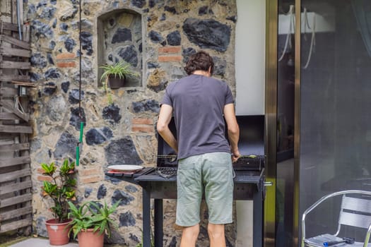 Man cooking dinner on a barbecue in his backyard. Outdoor cooking, home lifestyle, and family time concept.