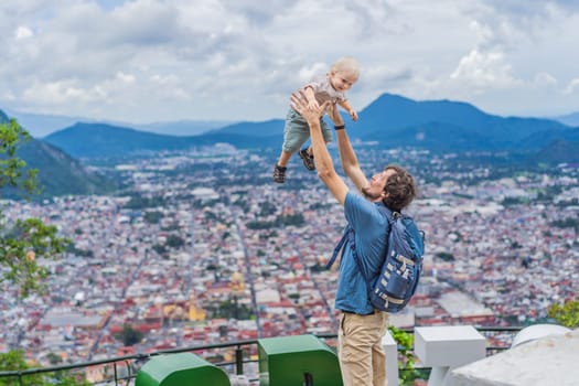 Dad and his baby son tourists in front of the panoramic view of Orizaba from Cerro del Borrego, Mexico. Travel, scenic landscape, and adventure concept.