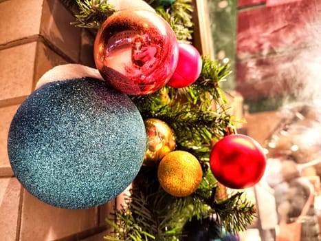 Glossy red, gold, and teal ornaments decorate a garland, creating a vibrant holiday atmosphere.