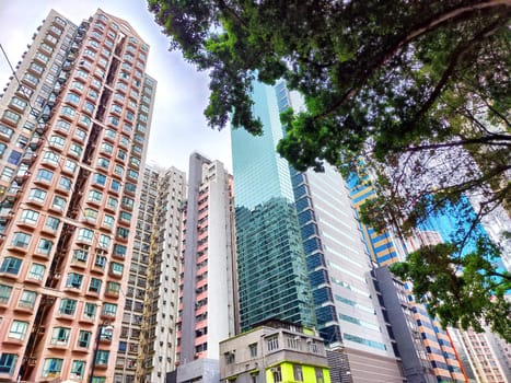 Towers dominate the skyline with a mix of modern and classic architecture under a cloudy sky.