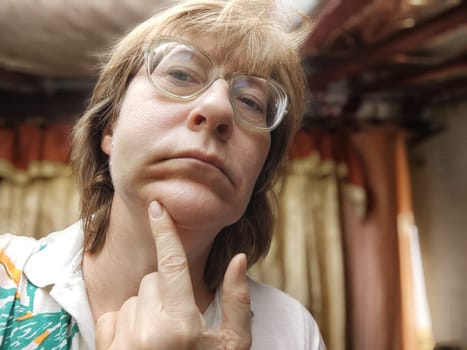 A woman shows a swollen cheek and bruise, indicating the aftermath of domestic abuse and dental issues in her home setting.