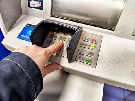 Kirov, Russia - September 20, 2024: A hand presses the button on an ATM, indicating a transaction for cash withdrawal in a bustling city environment.