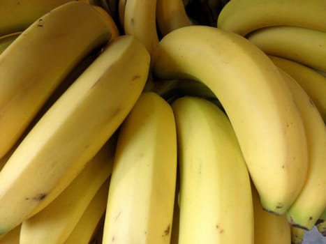 A fresh bunch of ripe bananas fills the view, showcasing their bright yellow skin and smooth texture, ready for purchase at the local market.