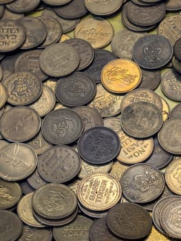 Honolulu - July 16, 2024: A variety of game tokens lie scattered across a table, showcasing different denominations and designs from a family entertainment locations in Hawaii including Carnival Carnival, Ice Palace, Jillians.