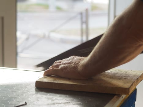 Construction worker is checking if a wooden plank is level by placing his hand on it. The image suggests precision and attention to detail in a construction setting