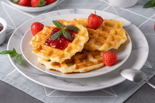 Waffles with strawberry jam and strawberries for breakfast.
