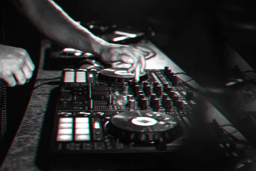 DJ mixes music on a professional controller Board in a nightclub at a party. 3D glitch effect